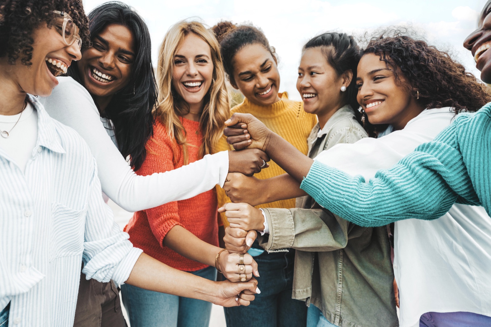 A multicultural group of women stacking their hands together